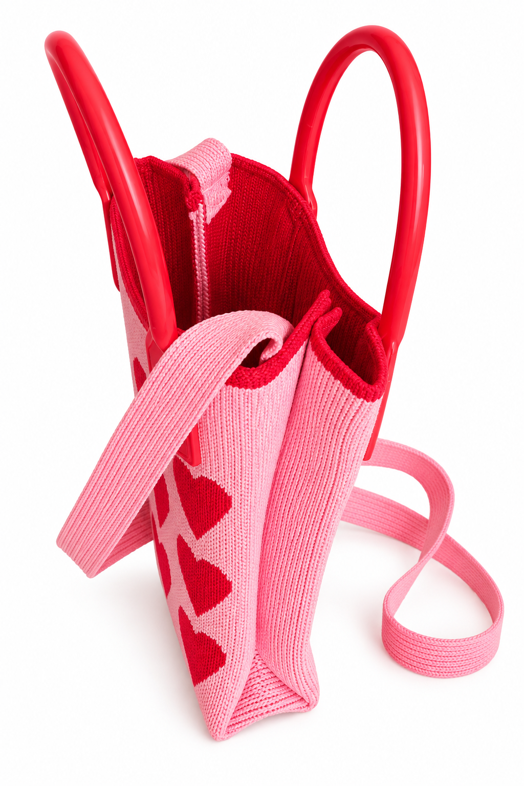 Side view showing the pink knit sides, red handles, and long shoulder strap of the purse